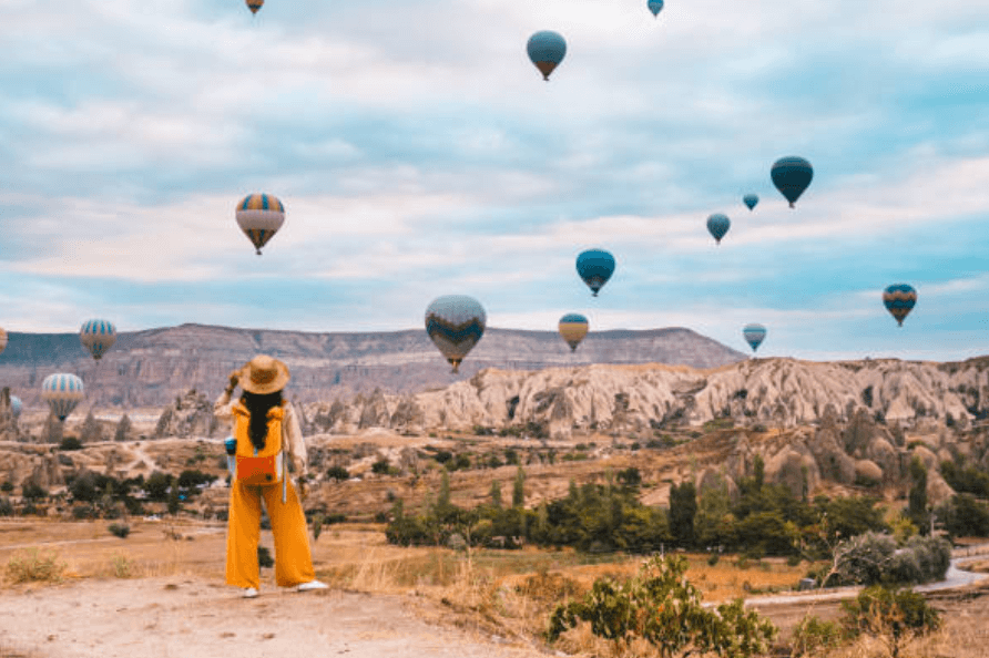 when is the best time to book trips for summer 2025 woman looking at hot air balloons